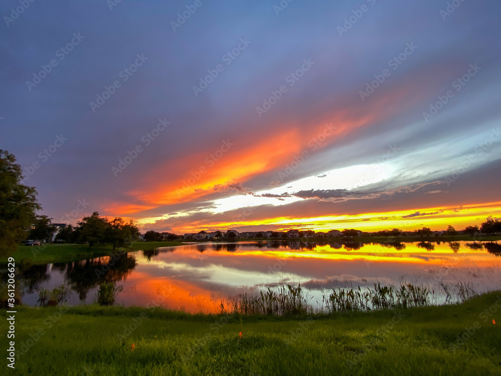 Obraz premium Beautiful pink, orange and blue sunset reflecting on a lake in a suburban neighborhood.
