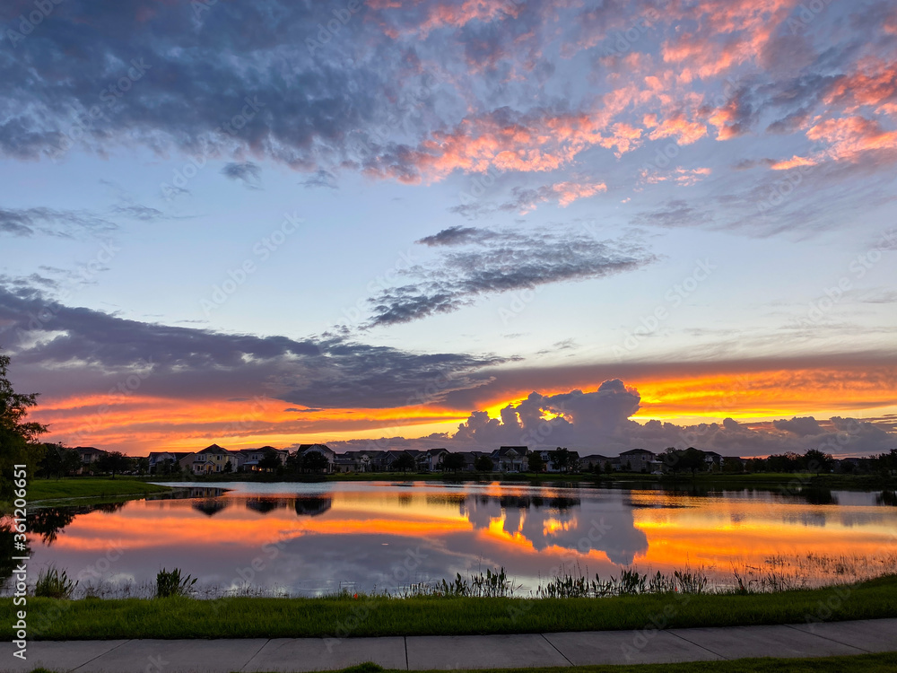 Obraz premium Beautiful pink, orange and blue sunset reflecting on a lake in a suburban neighborhood.