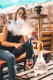 Young beautiful woman smoking hookah and having a great time
