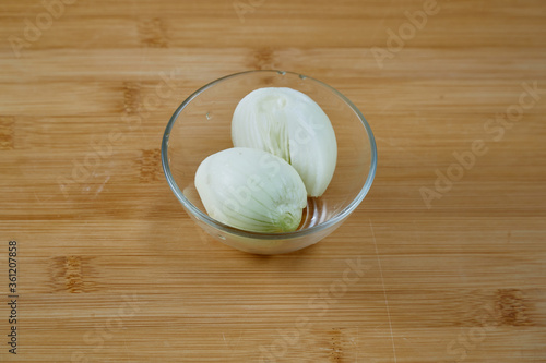 Whole onions in a glass plate on a wooden surface