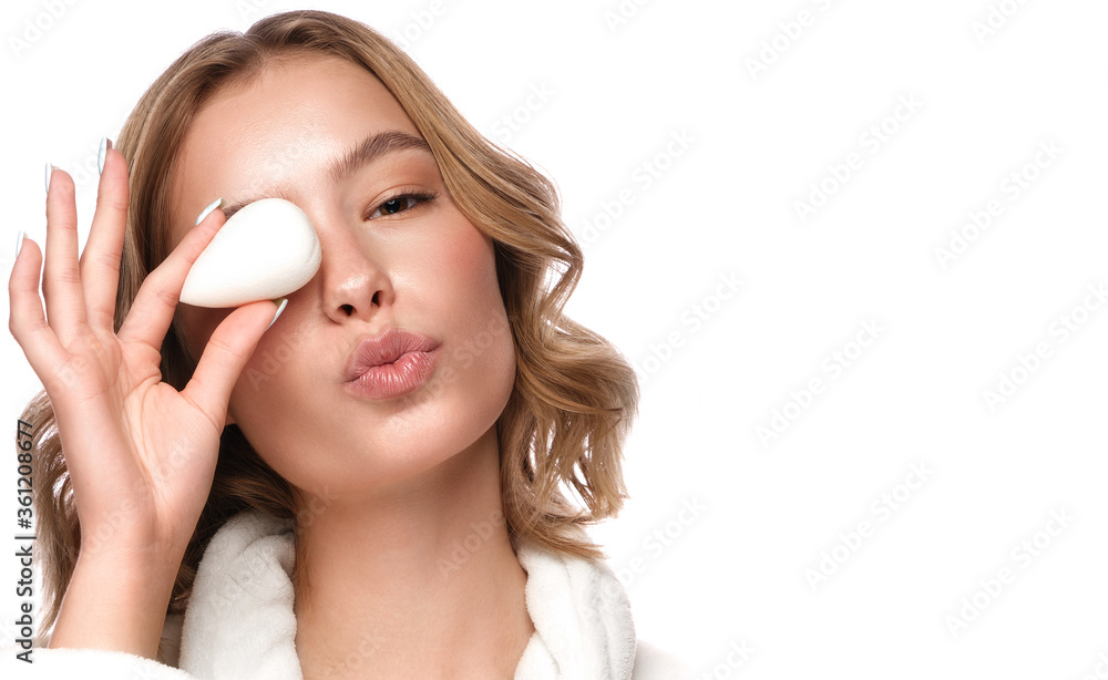 Beautiful tender young girl in a white coat with clean fresh skin posing in front of the camera with a sponge in her hands. Beauty face. Skin care. Beautiful tender young girl in a white coat with clean fresh skin posing in front of the camera with a sponge in her hands. Beauty face. Skin care.