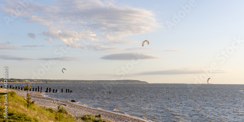 kitesurfers ride the sea on a sunny evening against the backdrop of a beautiful landscape