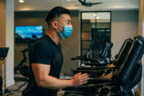 Asian male wearing mask running on treadmill during COVID19
