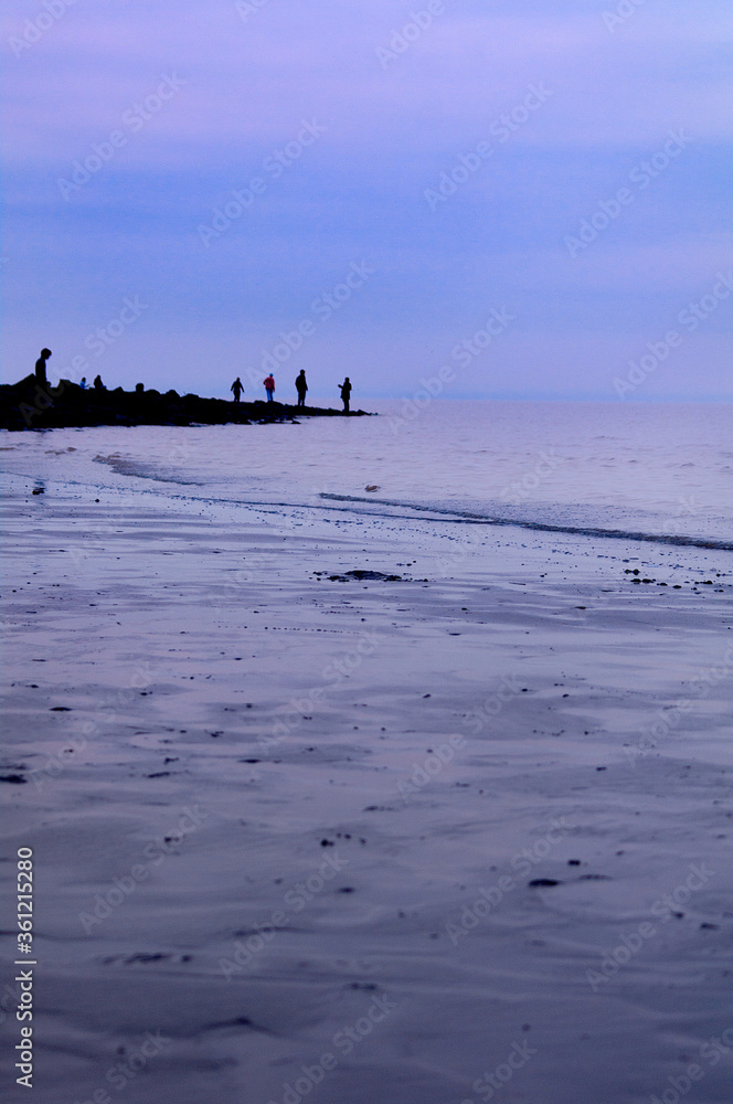 Silhouettes of people strolling on the beach