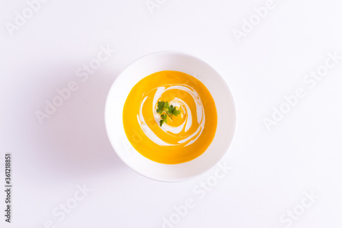 Tigela branca com creme de cenoura no prato branco mais pedaço de pão integral sobre a mesa branca photo