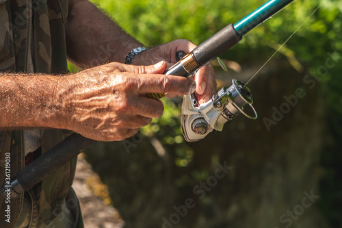 Older man hands holding fishing rod, enjoying retirement