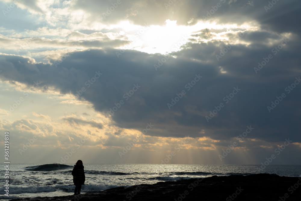 夕焼けに向かって立つ女性シルエット