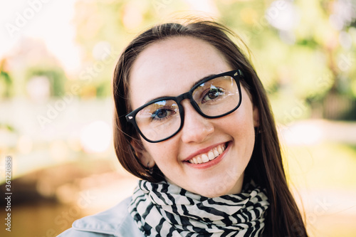 Portrait of a young beautiful caucasian girl with glasses in the park.