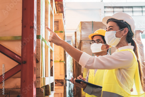 Asian engineer in helmet and face mask check parcel box in warehouse