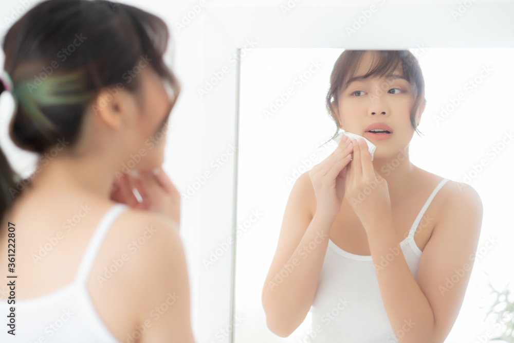 Beautiful young asian woman smiling with skin care cosmetic use oil blotting paper on face looking mirror at room, beauty asia girl wipe and cleansing makeup with tissue, clean on facial concept. Beautiful young asian woman smiling with skin care cosmetic use oil blotting paper on face looking mirror at room, beauty asia girl wipe and cleansing makeup with tissue, clean on facial concept.