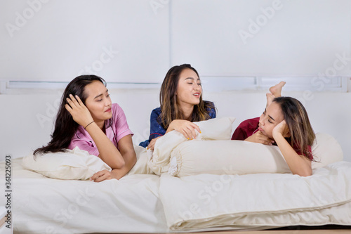 Group of teenage girls confiding together on bed