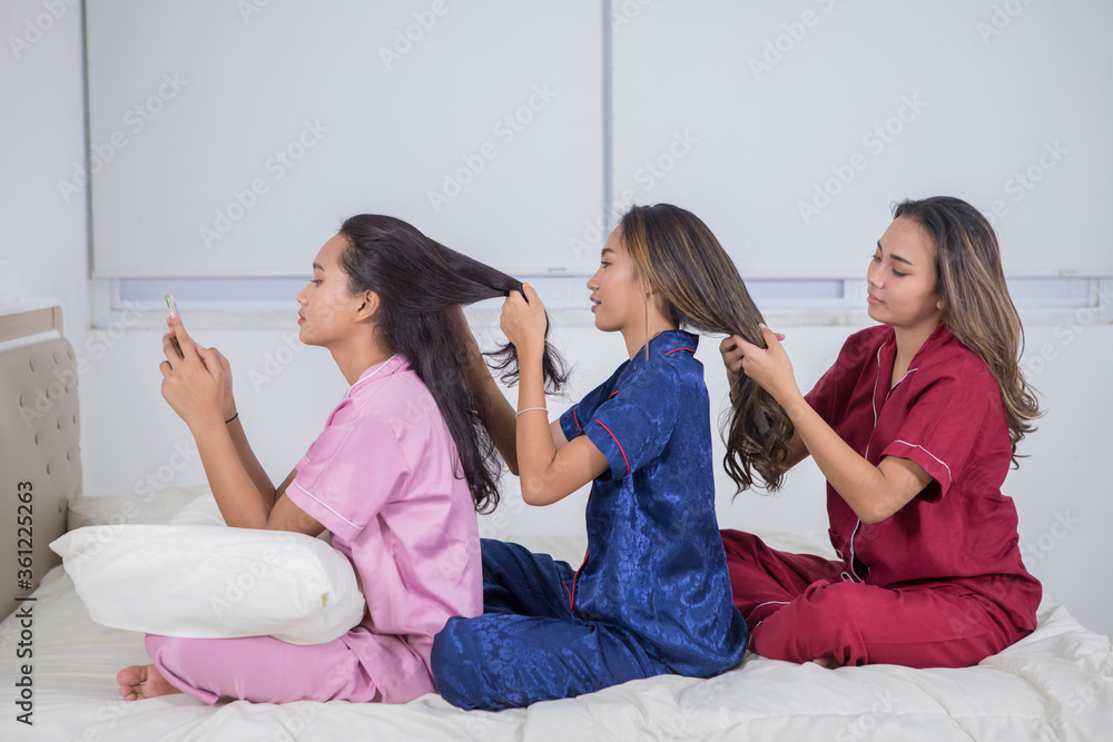 Group of teenage girls tying hair at sleepover party