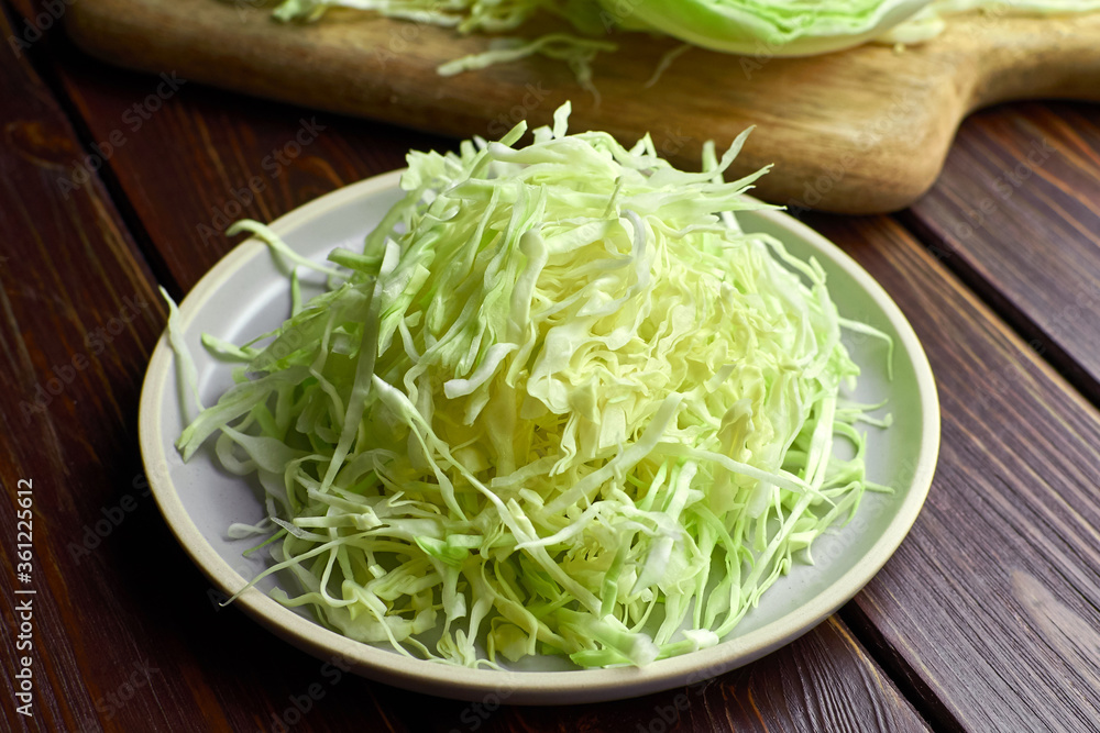 Plate with shredded white cabbage salad on dark woodden background. Plate with shredded white cabbage salad on dark woodden background.