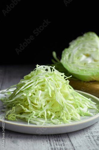 Dietary fresh chopped cabbage salad on ceramic plate over black background