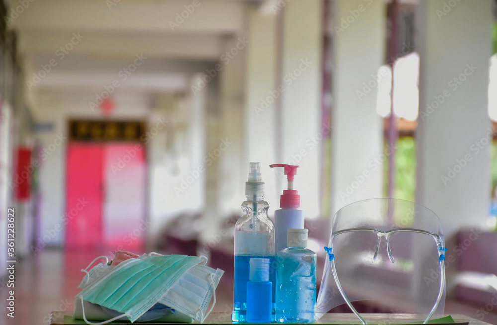 Medical masks, face shield, sanitizer, alcohol gel and hand soap on table in front of balcony to wear and to clean hands to prevent germs and protect coronavirus or covid-19 which is spreading now. Medical masks, face shield, sanitizer, alcohol gel and hand soap on table in front of balcony to wear and to clean hands to prevent germs and protect coronavirus or covid-19 which is spreading now.