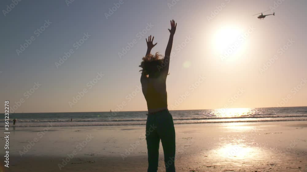 young woman frolics at the beach at sunset young woman frolics at the beach at sunset