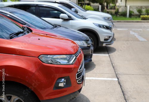 Closeup of front side of red car with other cars parking in outdoor parking area in bright sunny day.  © Amphon