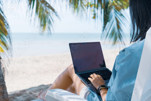 Woman using laptop and smartphone to work study in vacation cady at beach background. © ant