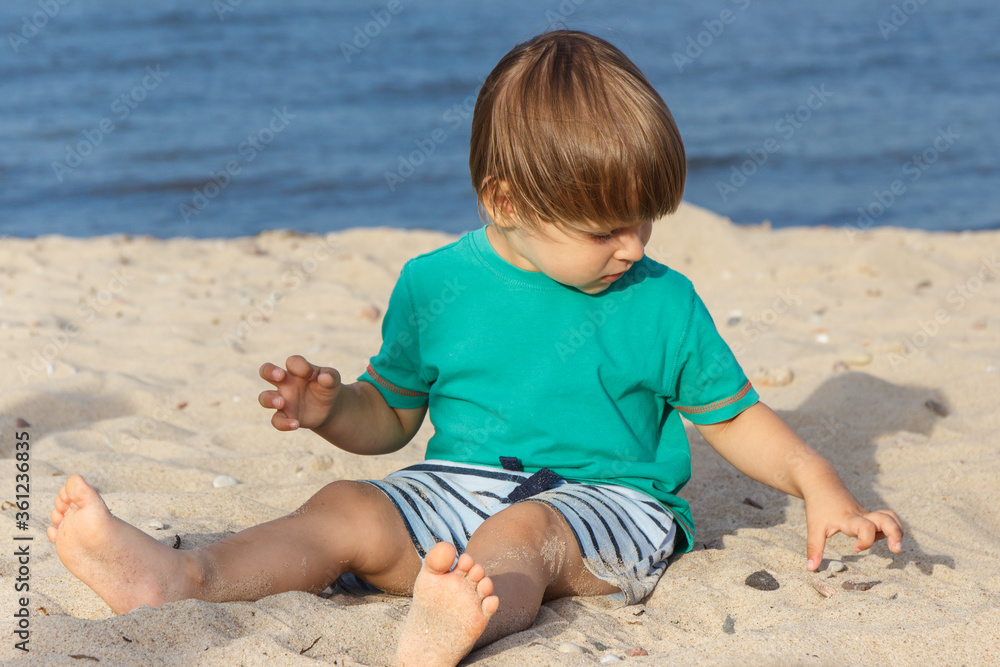 Baby boy on summer beach. Vacation time and child development concept Baby boy on summer beach. Vacation time and child development concept