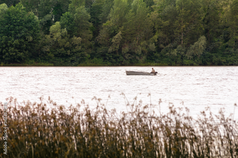 A fisherman on a boat on the Dnieper River in Kiev, Ukraine, between reeds and the forest A fisherman on a boat on the Dnieper River in Kiev, Ukraine, between reeds and the forest