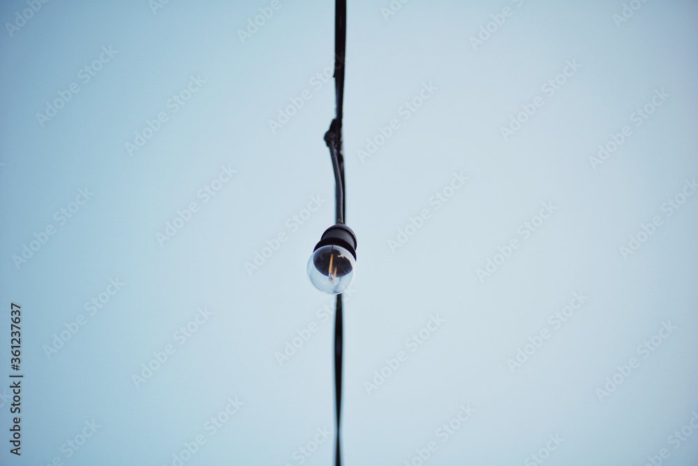 Light bulb hanging on a electricity wire with blue clear sky background. Light bulb hanging on a electricity wire with blue clear sky background.