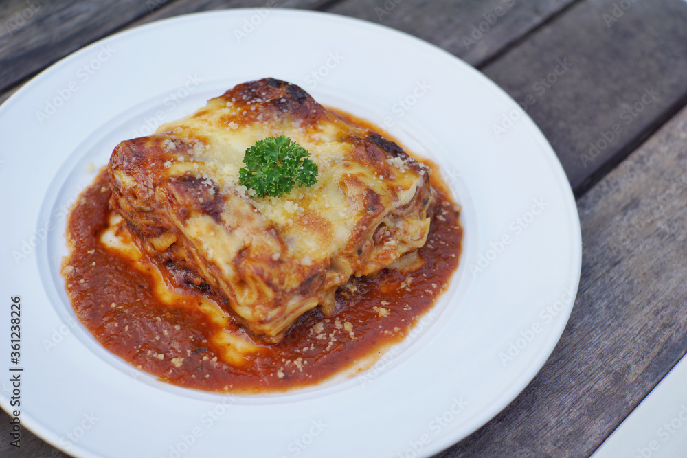 Close up of meat lasagna on a white plate with wooden table background. Close up of meat lasagna on a white plate with wooden table background.