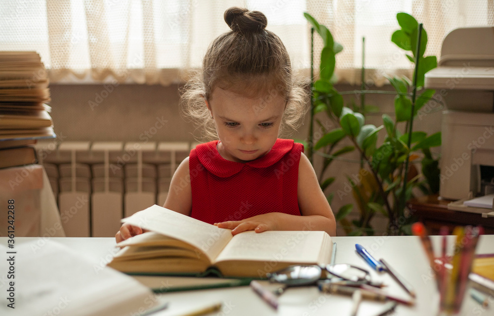 Little girl is reading a book with interest. Preschool education. Education and science. International Literacy Day. Little girl is reading a book with interest. Preschool education. Education and science. International Literacy Day.