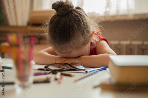 Preschool education. The little girl was tired of learning lessons and fell asleep at her desk. International Literacy Day. Education and science. Distance learning.