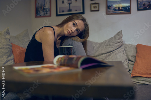 Girl in grey suit posing in cafe with magazine