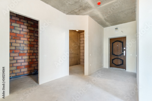 The hallway in an apartment in a new building without decoration. The new flat with the empty doorways and the white plastered walls