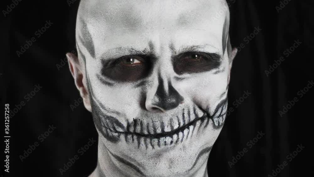 Man with make-up skeleton on a dark background. Halloween or horror theme. High quality 4k footage Man with make-up skeleton on a dark background. Halloween or horror theme. High quality 4k footage
