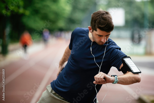 Young man checking his heart rate during work out. Young man exercising on athletics track 