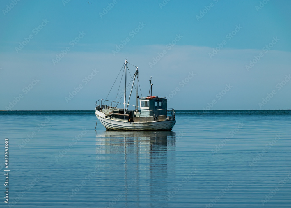 seascape with a small boat in calm water, sunny summer day, reflections in the water, Sorve Peninsula, Estonia