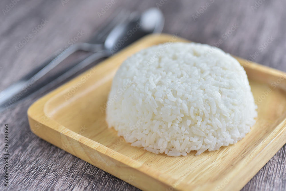 Steamed rice, cooked rice with spoon in wooden plate on grey wooden background Steamed rice, cooked rice with spoon in wooden plate on grey wooden background
