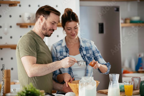 Young couple making pancakes together at home. Loving couple having fun while cooking.	