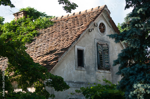 Attic tiled roof of an old house, window with shutters. Slovenia. photo