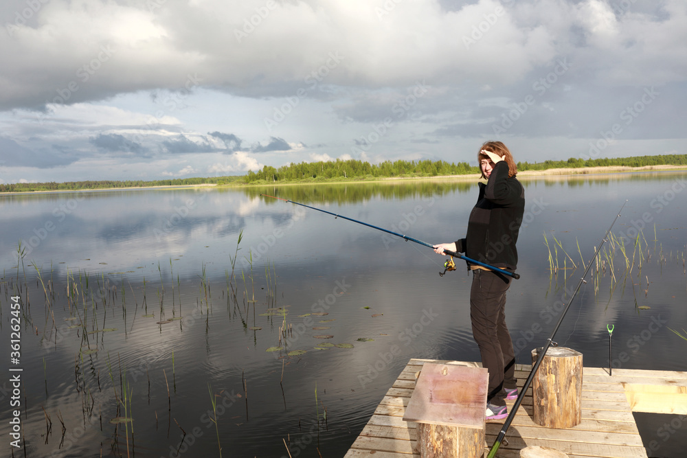 Woman fishing on wooden bridge at Seliger Lake