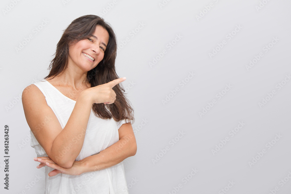 Good looking attractive middle-aged brunette woman with long hair, with a positive attitude, raises her left hand to show something Good looking attractive middle-aged brunette woman with long hair, with a positive attitude, raises her left hand to show something
