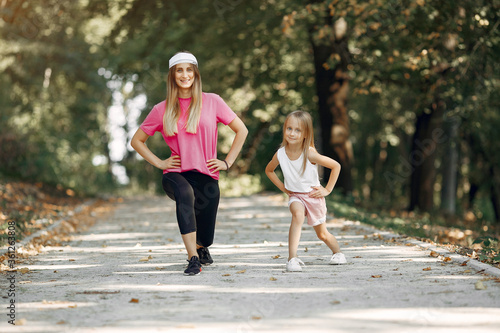 Beautiful mother with little daughter. Girls doing sport. Family in a sportswear. © prostooleh