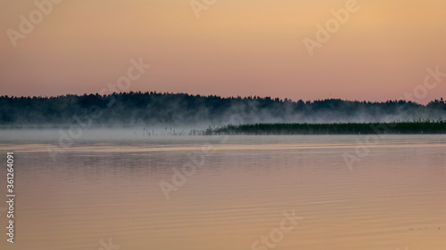 Fototapeta Naklejka Na Ścianę i Meble -  Foggy weather early in the morning on the lake. beautiful wallpapers. a mystical mist vibrates in the lake. summer sunrise