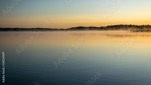 Foggy weather early in the morning on the lake. beautiful wallpapers. a mystical mist vibrates in the lake. summer sunrise © ANDA