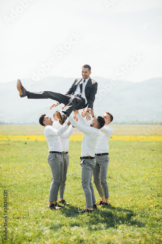 Groomsmen and groom posing outdoors on the wedding day. Funny wedding moment for best groom friends. Man hug each other