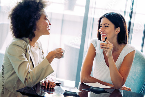Successful attractive women friends chatting in cafe during coffee break