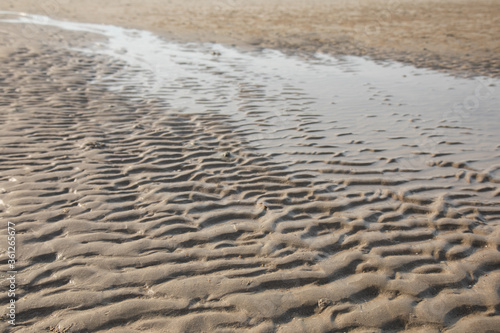 Texture of sand beach in waving with sea water