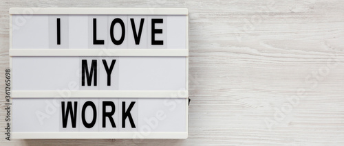 'I love my work' on a lightbox on a white wooden background, top view. Flat lay, from above, overhead. Copy space.