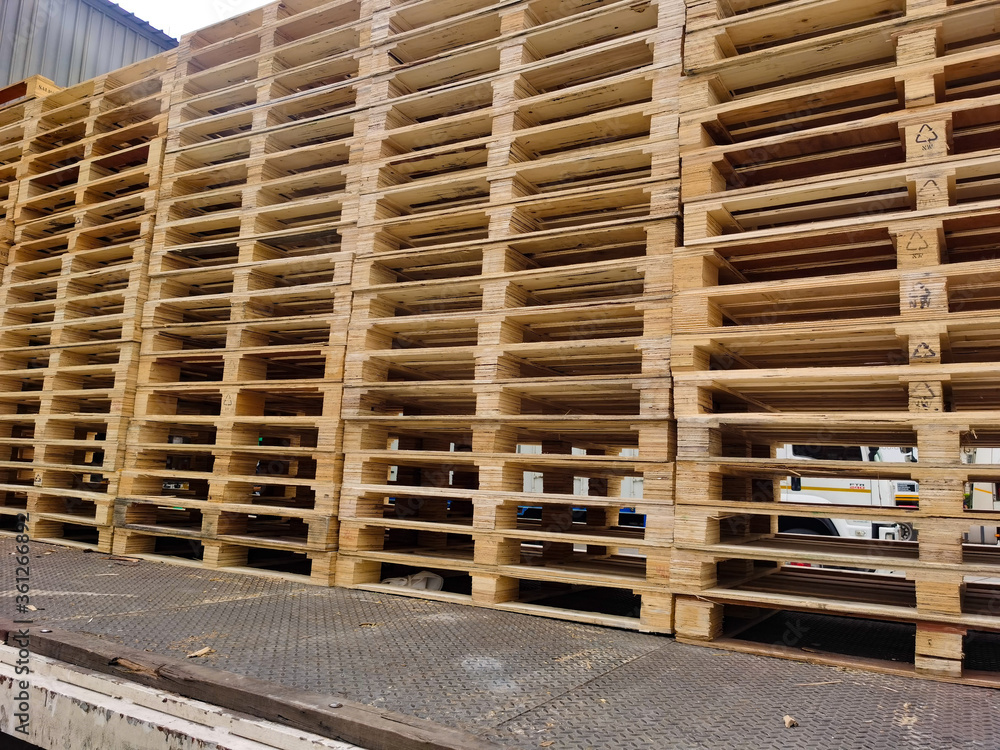Worker driving forklift truck to unload wooden pallets stack from truck to the cargo warehouse to support shipment for logistics and transportation industry Worker driving forklift truck to unload wooden pallets stack from truck to the cargo warehouse to support shipment for logistics and transportation industry
