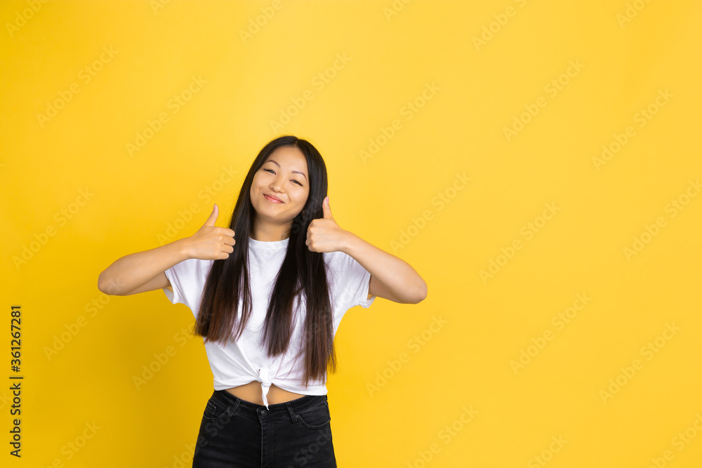 Thumb up, nice. Portrait of young asian woman isolated on yellow studio background. Stylish, trendy. Beautiful brunette model. Human emotions, facial expression, sales, ad, shopping concept. Copyspace Thumb up, nice. Portrait of young asian woman isolated on yellow studio background. Stylish, trendy. Beautiful brunette model. Human emotions, facial expression, sales, ad, shopping concept. Copyspace