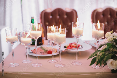banquet table is decorated with plates  cutlery  glasses  candles and flower arrangements