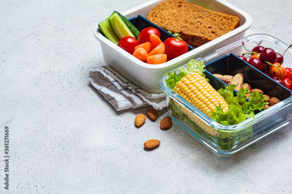 Lunch box with healthy fresh food. Sandwich, vegetables, fruits and nuts in a food container, light background.
