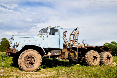Dirty truck on a country green grass in a sunny summer day with blue sky.